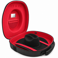 Voyager hat travel case open, showing the Signature Red suede-lined interior with a black felt hat secured under crossed straps